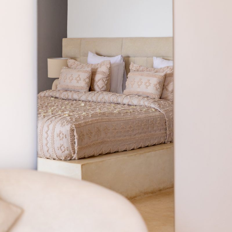 Detail of a suite bed dressed in ivory textured linens
