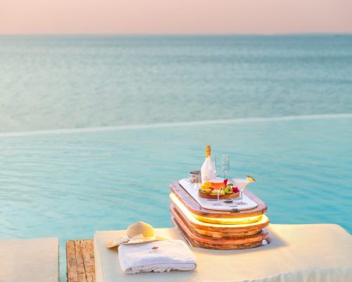 Champagne and fruit served on a floating tray at the infinity pool edge overlooking the Indian Ocean