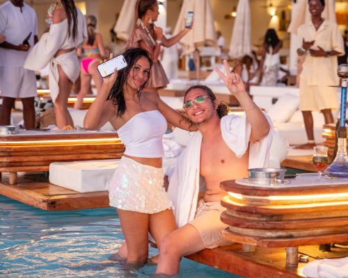 Guests celebrating on a lit floating sunbed during a Le Saint Tropez pool party